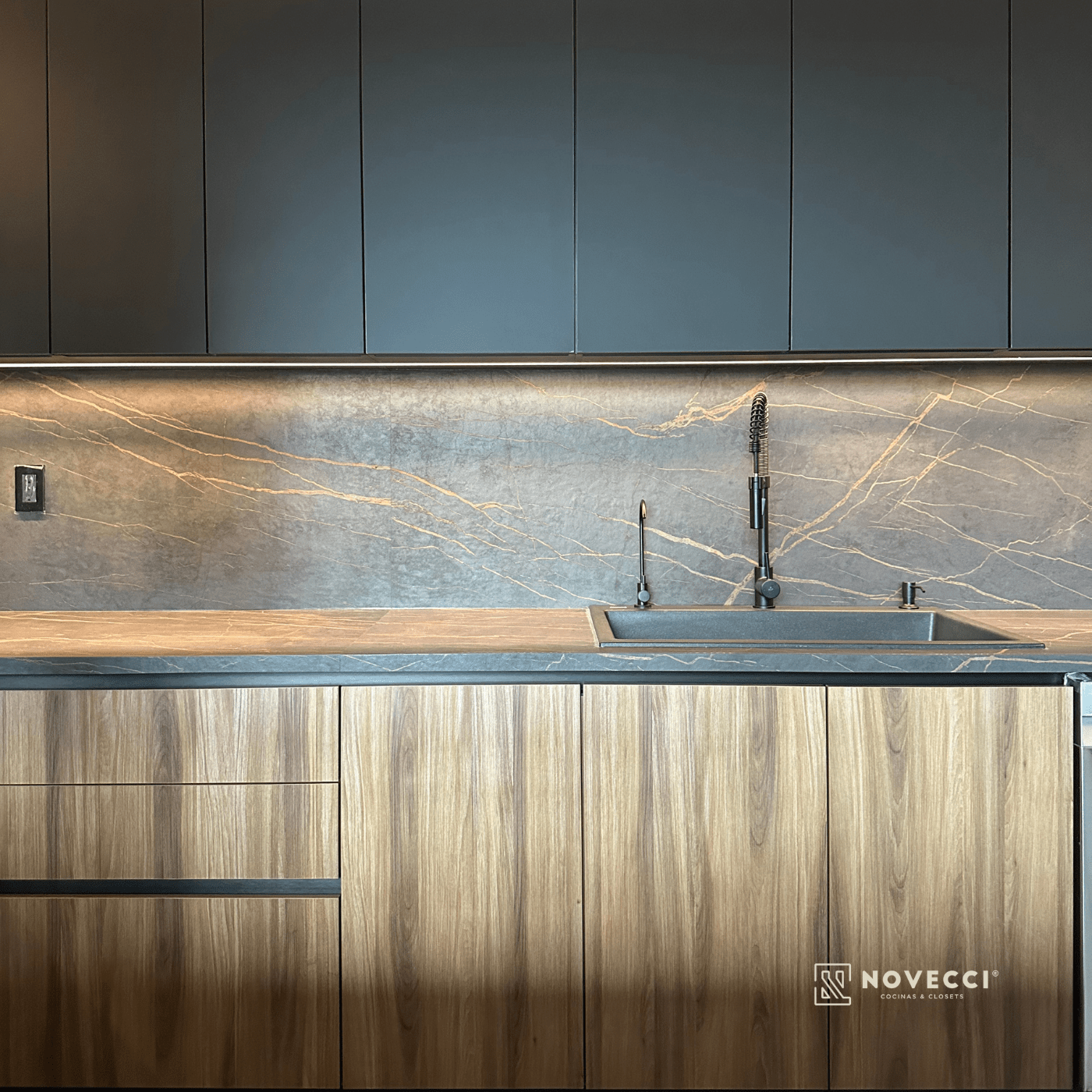 Detalle de cocina Novecci con mobiliario oscuro y cubierta de piedra